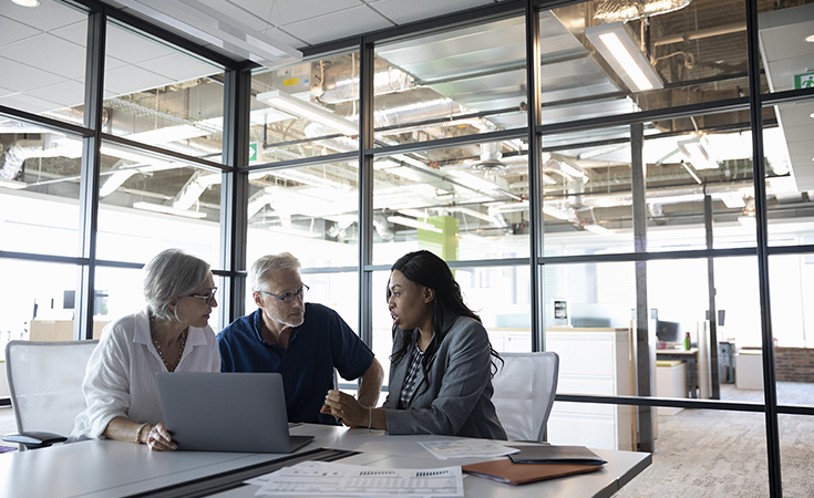 financial professional sitting down in an office talking with older couple