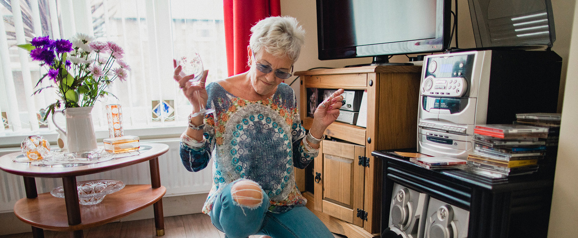 older woman listening to music and holding a wine glass