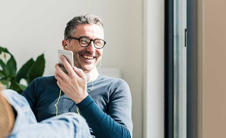 man smiling while listening to something on his phone