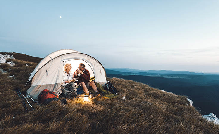 older couple sitting in a tent in the outdoors